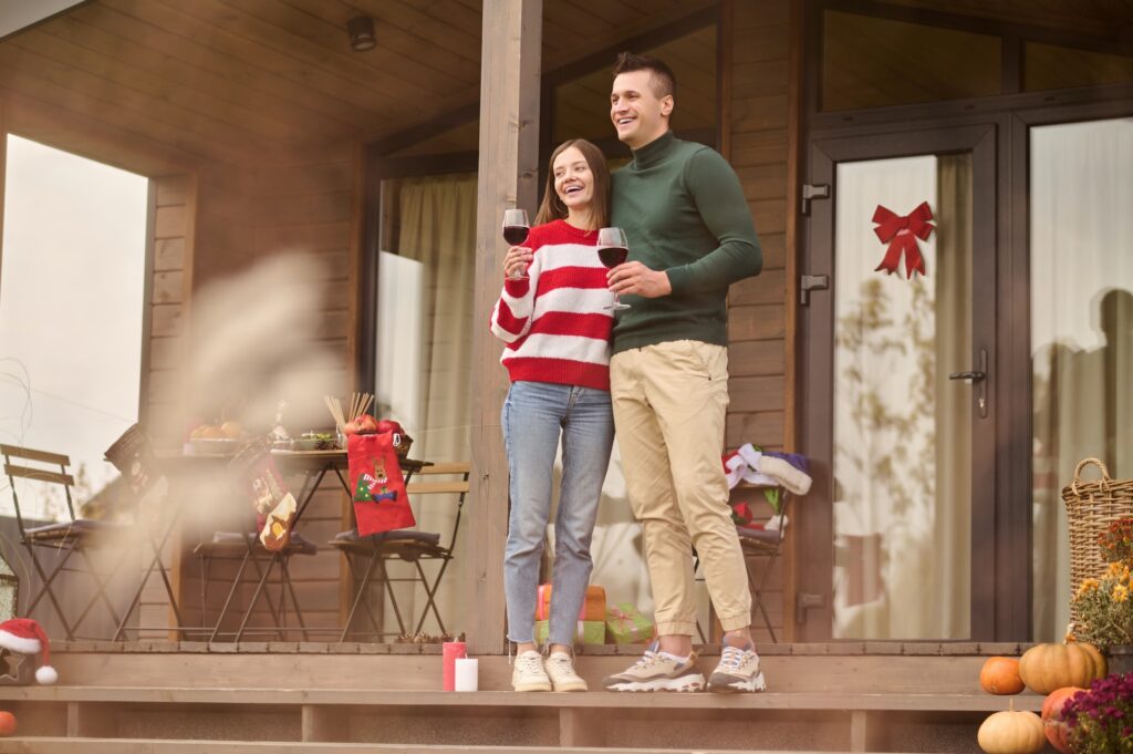 A young couple stadning near the house and looking happy